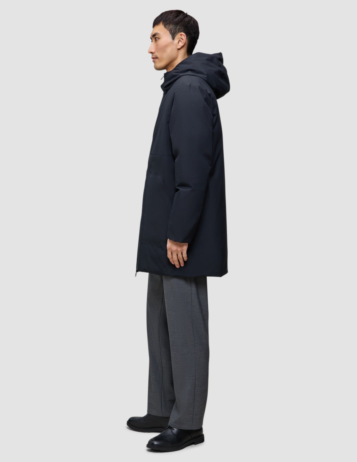 En man klädd i en svart Utility Jacket och svarta och grå byxor.